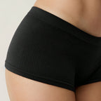 Black Shelliy Brief Side Hip Close-up On Beige Backdrop — On-body
